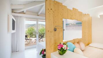 Una camera da letto con una testiera in legno, un letto con cuscini, un comodino e una finestra vista fenicotteri su una spiaggia.