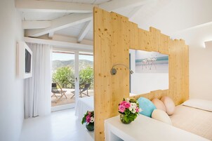 Una camera da letto con una testiera in legno, un letto con cuscini, un comodino e una finestra vista fenicotteri su una spiaggia.