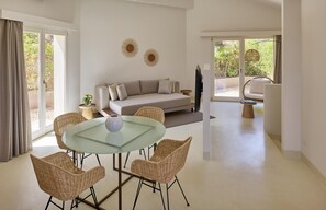 A modern living room with a glass table, wicker chairs, a sofa, and a TV. - Baia di Chia Resort Sardinia, Curio Collection (Domus de Maria)