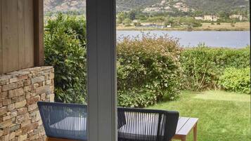 Un patio con dos sillas y una mesa, con vista a un lago y colinas.
