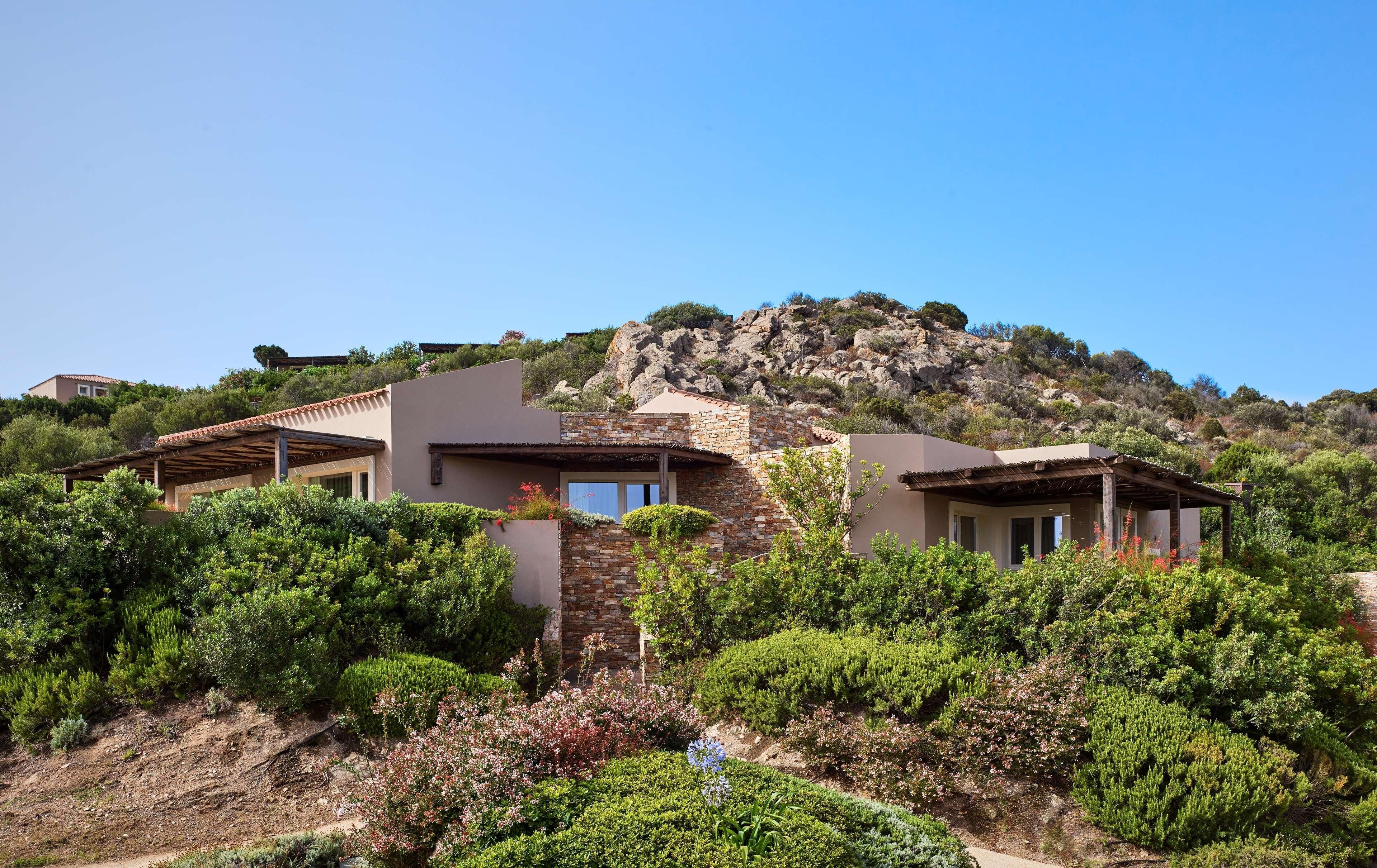 A hillside villa with a stone facade, multiple rooms, and a view of the surrounding landscape.