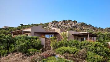 A hillside villa with a stone facade, multiple rooms, and a view of the surrounding landscape.