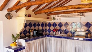 A kitchen with blue and white tiles, wooden beams, a stove, and a sink.