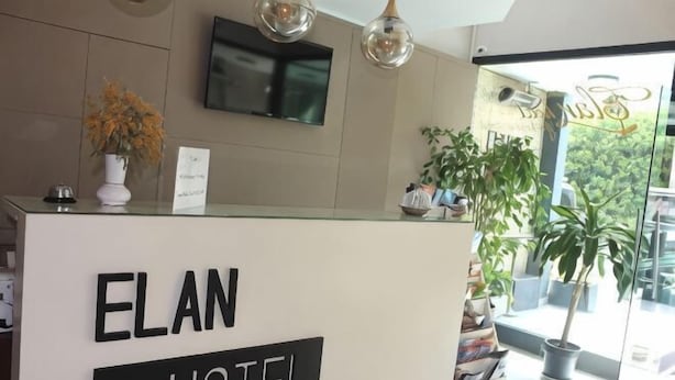 A reception desk at the Elan Hotel with a modern design, a flat-screen TV mounted above, and potted plants on the right. - Elan Hotel Istanbul Pera (Istanbul)