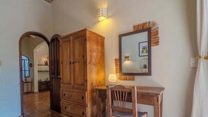 Ein Holztisch mit Stuhl, einem Spiegel und einer Lampe in einem Zimmer mit Fliesenboden und einem Holzschrank.