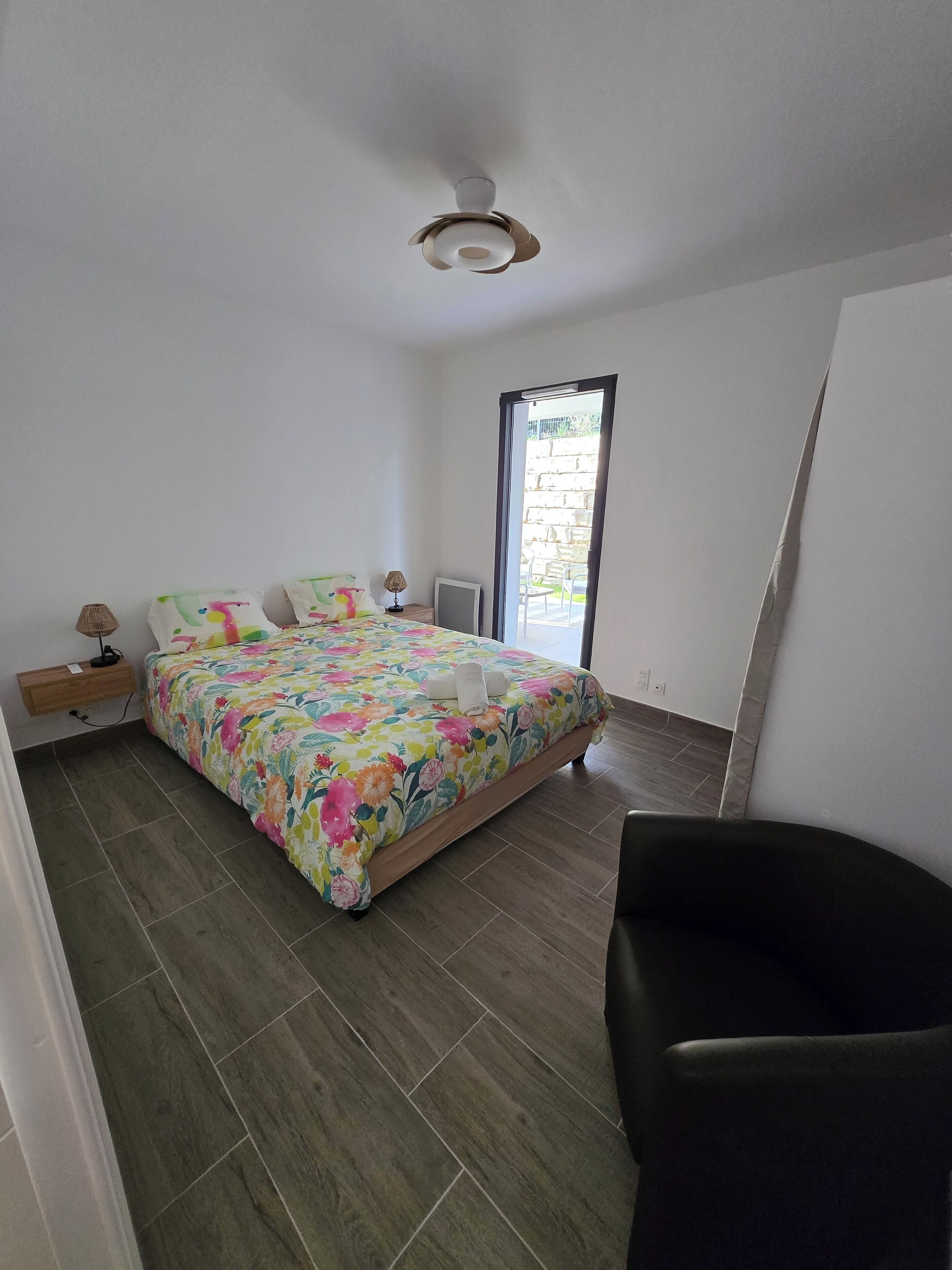 Een slaapkamer met een bed, nachtkastje, lamp en uitzicht.
