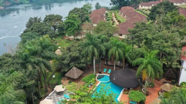 A resort with a swimming pool surrounded by lush greenery and a river in the background.