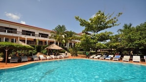 A swimming pool with lounge chairs and a building with balconies in the background.