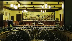 A restaurant with a long counter, hanging lights, and a large painting on the wall. - Jinja Nile Resort (Jinja)