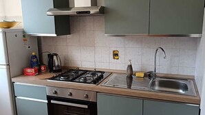 A compact kitchen with a gas stove, oven, and a sink. - Apartment in the center of Serravalle at 5min from the outlet Serravalle Mcarthurglen (Serravalle Scrivia)