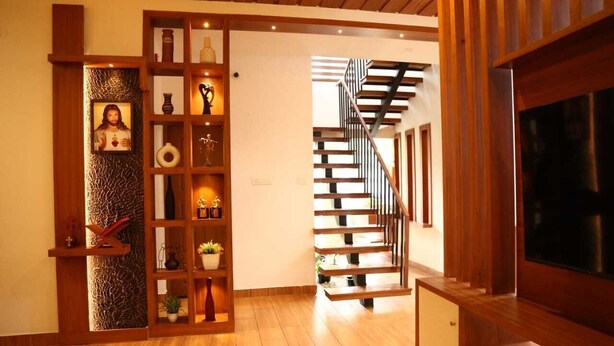 Eine Holztreppe führt zu einer zweiten Etage, ein Holzregal mit verschiedenen Gegenständen und ein Fernseher auf der rechten Seite.