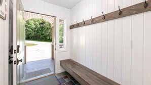 A hallway with a wooden bench, a coat rack, and a door leading outside.