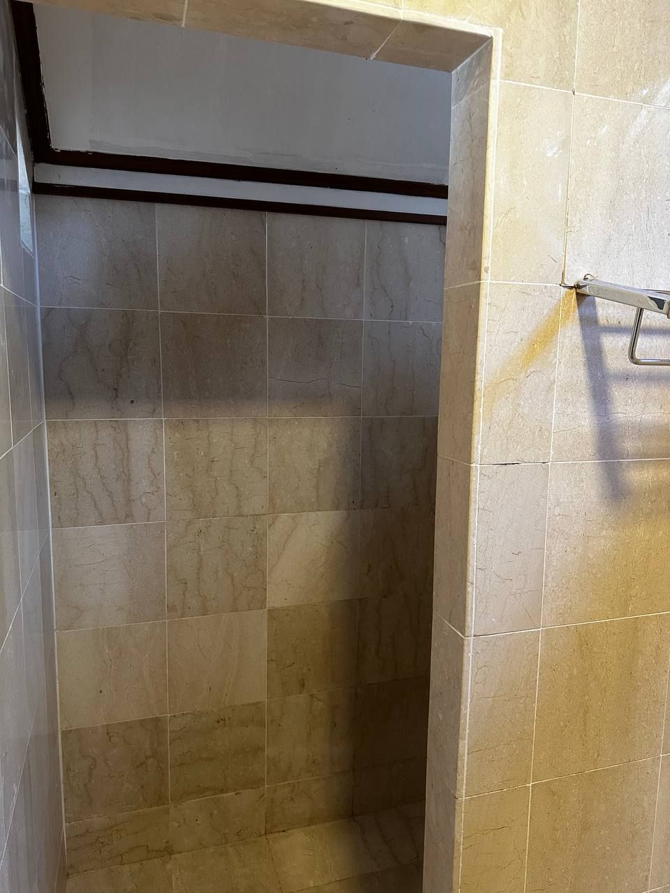 Une zone de douche carrelée avec une fissure visible dans le mur.