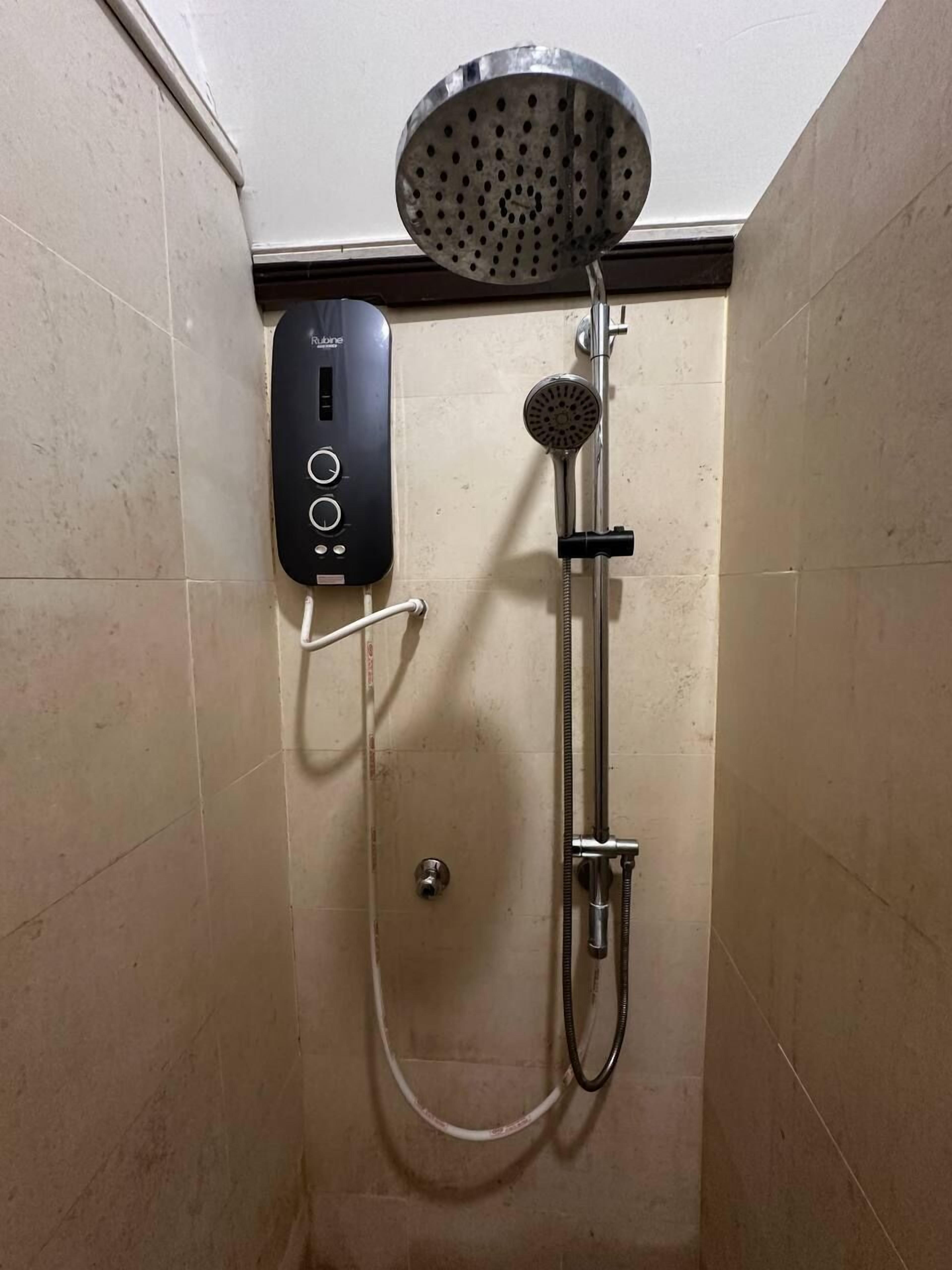 A shower with a handheld showerhead and a wall-mounted control panel.