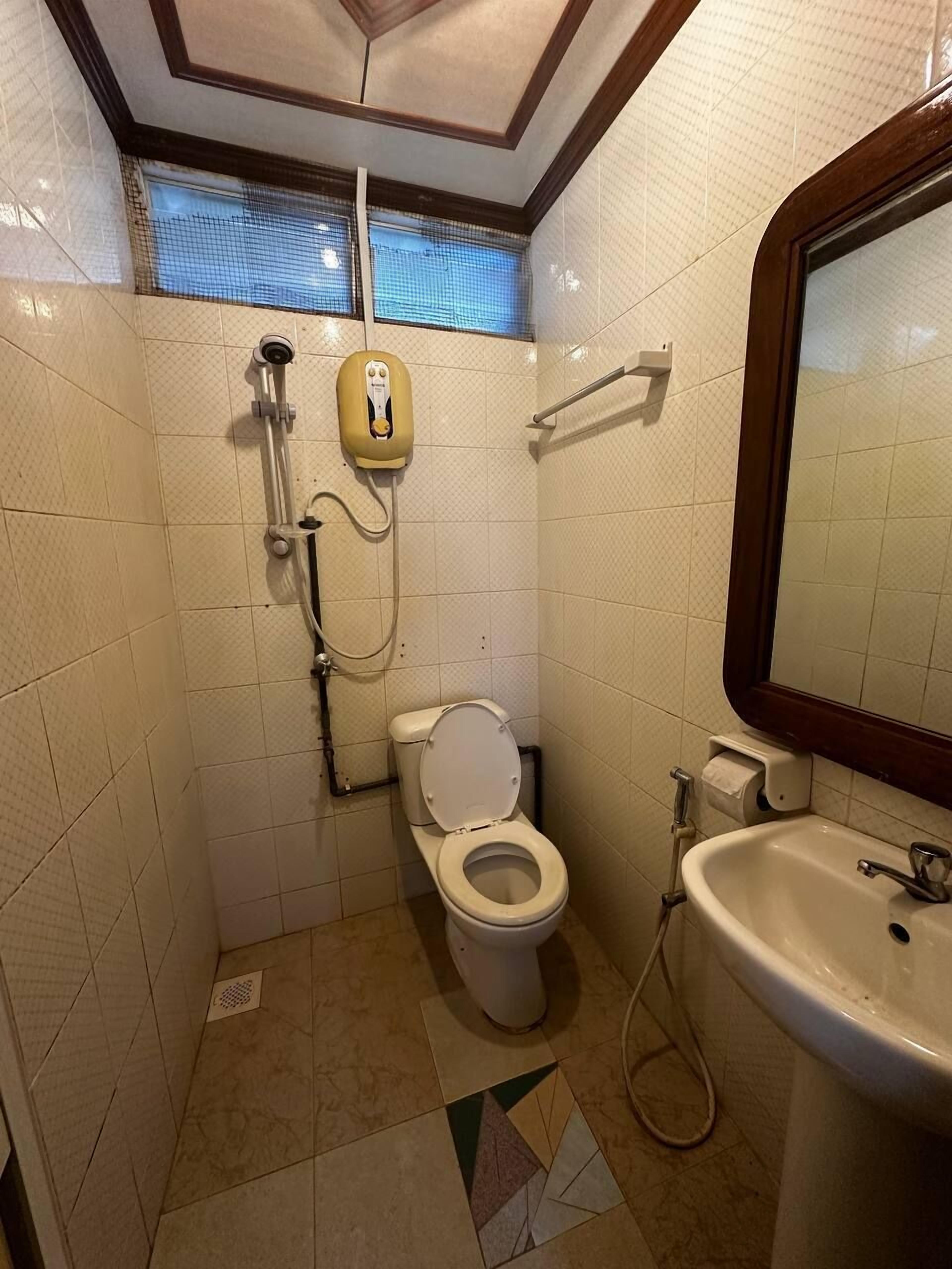 Pieni kylpyhuone, jossa on wc, pesuallas ja suihku.