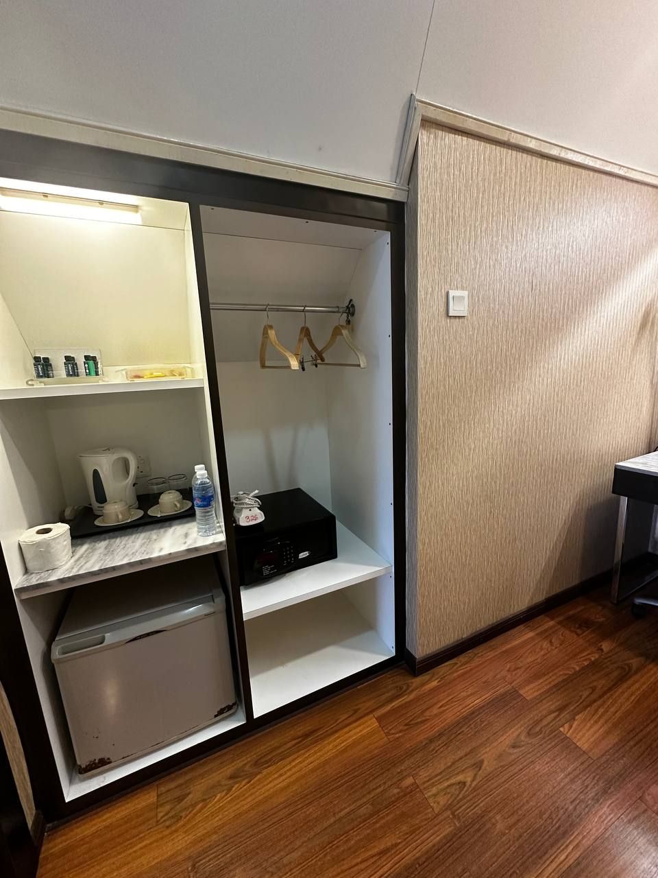 A compact room with a built-in wardrobe, a small kitchenette, and a wooden floor.