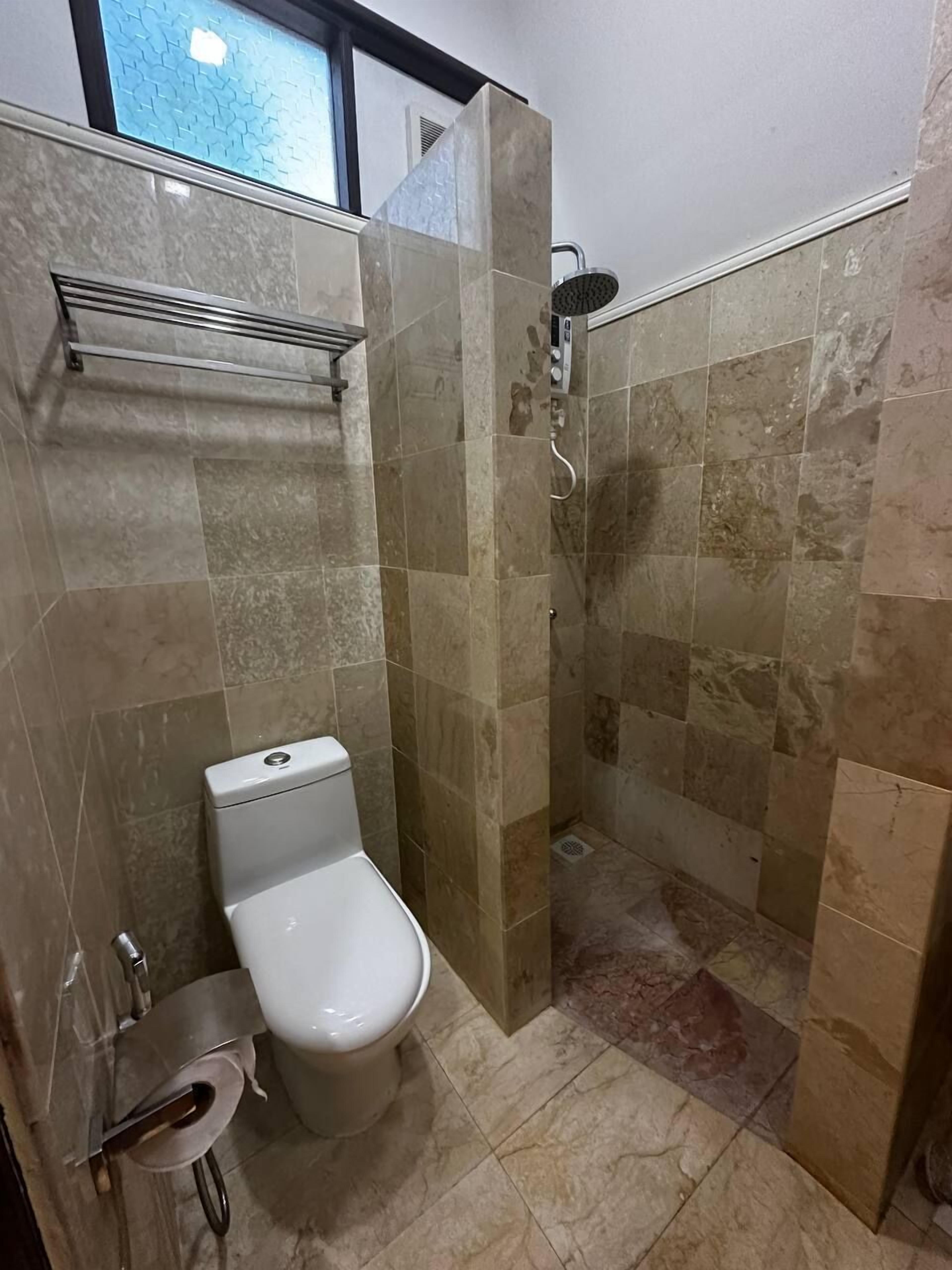 A bathroom with a toilet, a shower, and a towel rack.