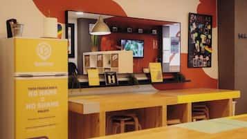 Um balcão com geladeira, quadro de menu e tela de televisão.
