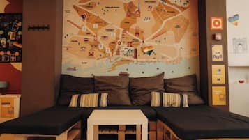 Quarto com um grande mapa de Barcelona, duas camas, uma mesinha e uma parede com várias decorações.