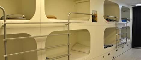 Camera con letto a castello, scaffali e cassetti integrati, caratterizzata da un design moderno con pareti curve e un'estetica minimalista.