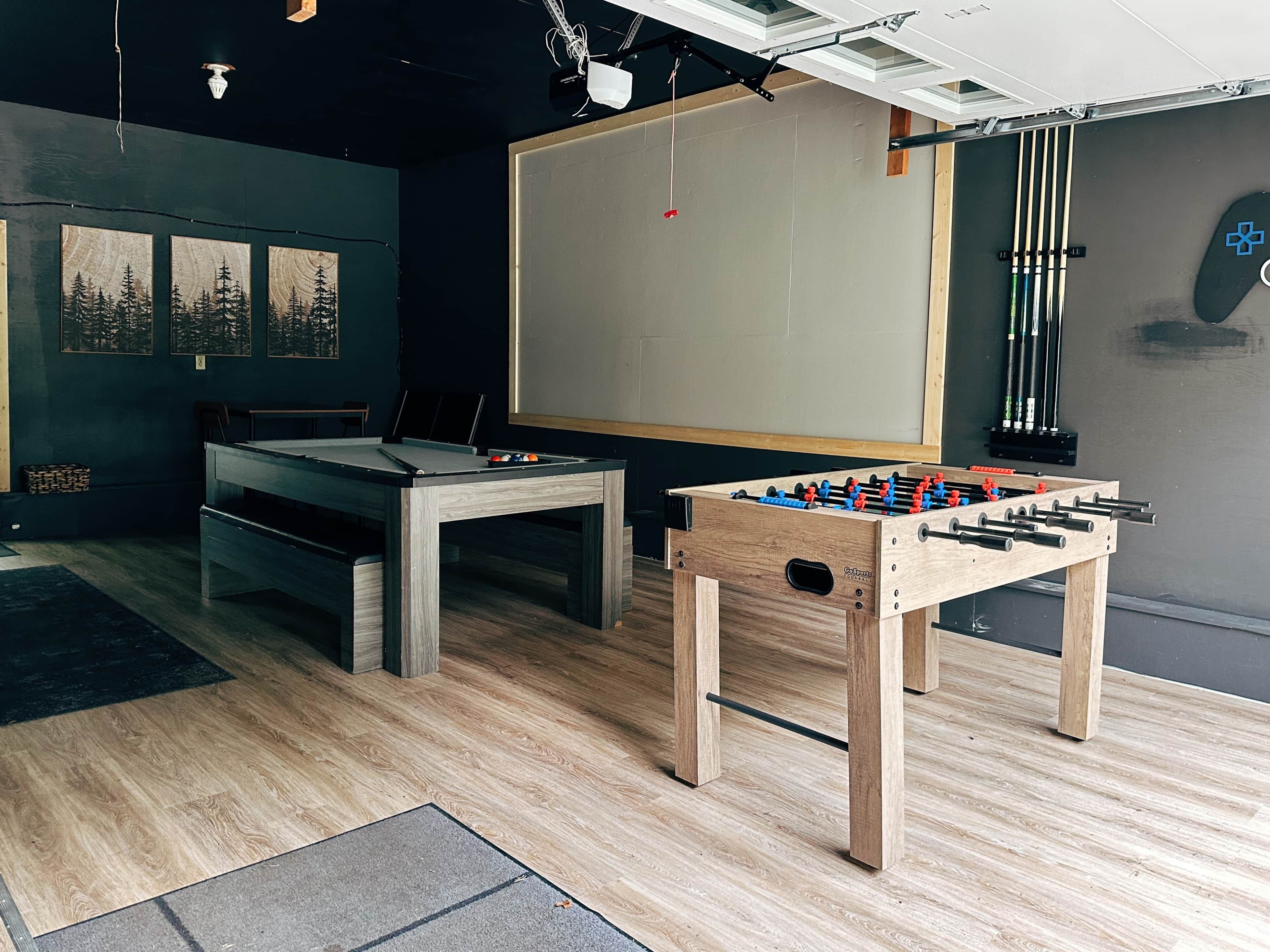 Une pièce équipée d’une table de billard, d’un baby-foot, d’un tableau blanc et d’un projecteur fixé au plafond.