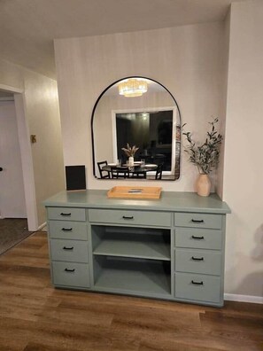 Een lichtblauwe kaptafel met een spiegel, een dienblad en een potplant.