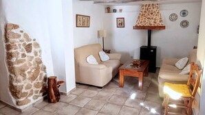 Un accogliente soggiorno con parete in pietra, due divani color beige, un tavolino in legno e un camino.