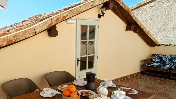 Zona pranzo con tavolo apparecchiato per la colazione, con piatti, tazze e un cesto di arance.