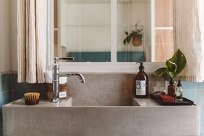 Un baño con un lavamanos moderno, un espejo y una ventana.