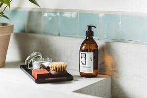 Una encimera de baño con una botella de jabón líquido, un cepillo de dientes y un cepillo para el cabello.
