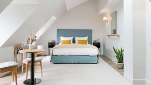 Un dormitorio moderno con cama, mesitas de noche, una mesa redonda y sillas.
