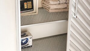 Quarto compacto com cama, micro-ondas e pequeno armário.