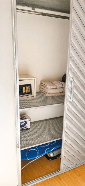 Quarto compacto com cama, micro-ondas e pequeno armário.