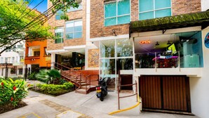 A building with a staircase leading to an entrance, a motorcycle parked outside, and a sign indicating the establishment is open. - Luxury Laureles LA 70-Medellin Stunner (Medellín)