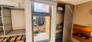 A room with a large window, a metal rack, a wooden bench, and a shelving unit with folded towels. - Luxury Laureles LA 70-Medellin Stunner (Medellín)