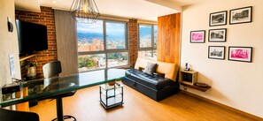 A modern living room with a glass desk, a sofa, a TV, and a city view. - Luxury Laureles LA 70-Medellin Stunner (Medellín)