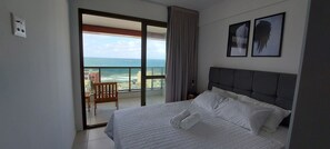 Un dormitorio con una cama grande, vista al océano, una silla y un balcón con vistas.