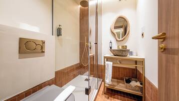 A modern bathroom with a glass-enclosed shower, a bathtub, a vanity with a large bowl sink, and a mirror with a wooden frame.