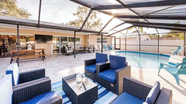 A covered outdoor area with a pool, lounge chairs, and a table. - Heated Private Pool + Game Room | Family & Group Favorite | Beach Minutes Away (Largo)