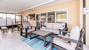 A covered outdoor seating area with a sofa, chairs, and a table. - Heated Private Pool + Game Room | Family & Group Favorite | Beach Minutes Away (Largo)
