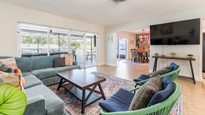 A spacious living area with a sofa, chairs, a coffee table, and a TV. - Heated Private Pool + Game Room | Family & Group Favorite | Beach Minutes Away (Largo)