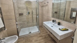 A modern bathroom with a glass-enclosed shower, a white sink, and a large mirror. - RESIDENZE SERVENTI LONGHI (Rome)