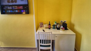 A compact room with a yellow wall, a flat-screen TV mounted above a white table, and a small white refrigerator. - RESIDENZE SERVENTI LONGHI (Rome)