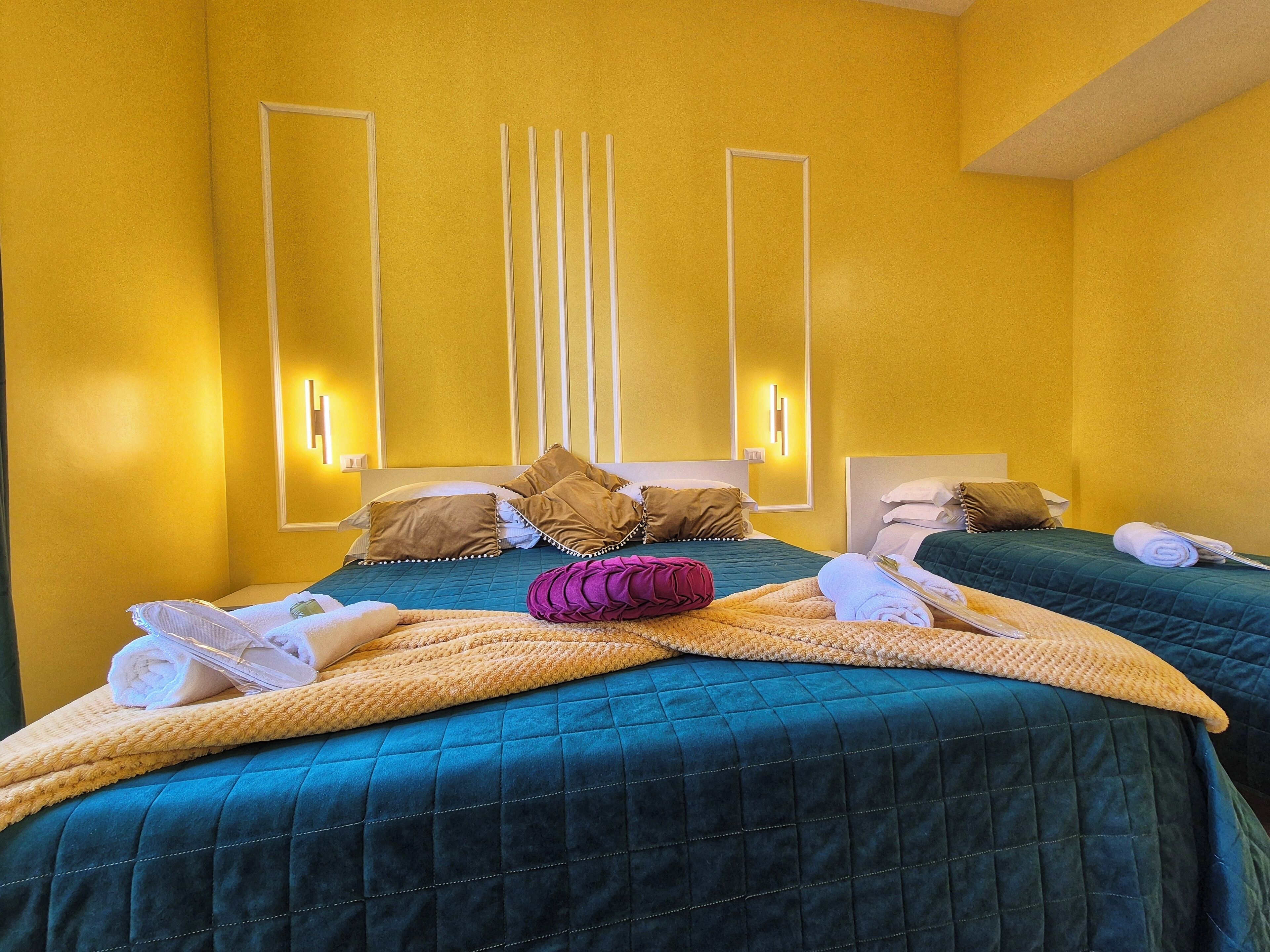 A hotel room with two beds, yellow walls, and modern lighting fixtures.