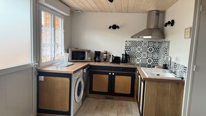 A compact kitchen with a washing machine, microwave, and a coffee maker. - Gîte Lucanna Apartment with terrace for 5 people (Unknown)