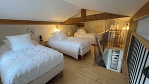A bedroom with two beds, wooden floors, a staircase, and a wooden ceiling. - Gîte Lucanna Apartment with terrace for 5 people (Unknown)