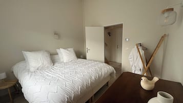 Een slaapkamer met een bed, nachtkastje en een houten stoel.