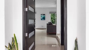 Un pasillo moderno con una puerta cerrada, un sofá gris y un cuadro en la pared.