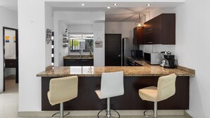 Una cocina moderna con armarios oscuros, encimera de granito y dos taburetes de bar.