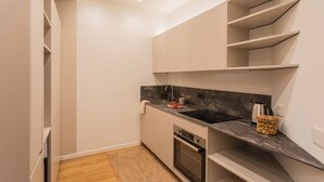 A modern kitchen with white cabinetry, a black countertop, and a built-in oven.